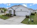 One-story house with white exterior, two-car garage, and well-maintained lawn at 33571 Sky Blossom Cir, Leesburg, FL 34788