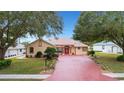 Charming single-story home with red front door and brick paved driveway at 5509 Grove Mnr, Lady Lake, FL 32159