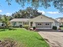 Single-story house featuring a green lawn and attached garage at 1310 Moray Ct, Leesburg, FL 34788