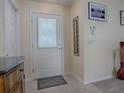 Bright foyer with a white door, decorative mirror, and sleek tile flooring at 1500 Alexa Pl, The Villages, FL 32162