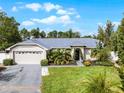 Single-story home with a two-car garage, lush landscaping, and a paved driveway at 240 Citrus Wood Ct, Davenport, FL 33837