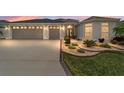 Charming home exterior at dusk, featuring warm lighting and lush landscaping at 3766 Causey Ct, The Villages, FL 32163