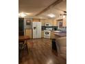 Bright kitchen with white appliances, wood-look flooring, and a dining area at 12141 Lake Pines Rd, Leesburg, FL 34788