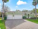 Green two-story home with a three-car garage and a brick paved driveway at 3556 Creek Run Ln, Eustis, FL 32736