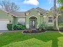 Front view of a green home with landscaping and a walkway to the front door at 3556 Creek Run Ln, Eustis, FL 32736
