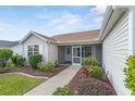 Tan house with landscaped yard, screened porch, and attached garage at 17848 Se 87Th Bourne Ave, The Villages, FL 32162
