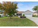 Tan house with a two-car garage and lush landscaping at 17848 Se 87Th Bourne Ave, The Villages, FL 32162