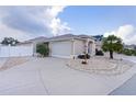 Front view of a lovely tan house with palm trees and a white fence at 1808 Dalton Dr, The Villages, FL 32162