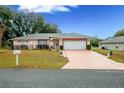 Charming one-story home, featuring a two-car garage and manicured lawn at 202 Forest Park Ln, Lady Lake, FL 32159
