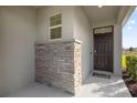 Front entrance with a dark brown door and stone accents at 8128 Penrose Pl, Wildwood, FL 34785