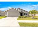 Single-story house with gray siding, two-car garage, and manicured lawn at 16178 Se 104Th Ter, Summerfield, FL 34491