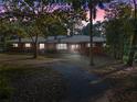 Brick home with metal roof, long driveway, and mature landscaping at dusk at 22740 County Road 44A, Eustis, FL 32736