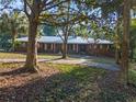 Brick ranch home with metal roof and long driveway, framed by trees at 22740 County Road 44A, Eustis, FL 32736