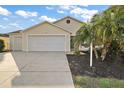 House exterior featuring a two-car garage and palm trees at 3810 Cosmos Way, The Villages, FL 32163