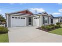 Two-car garage with gray siding and red accents at 5820 Bamboo Ave, The Villages, FL 32163