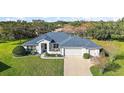 One-story home with a blue roof, two-car garage, and landscaped yard at 27437 Desert Rose Ct, Leesburg, FL 34748