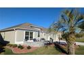 Landscaped yard with seating area next to two-car garage at 1881 Sassparilla Way, The Villages, FL 32162