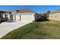 View of the back of the house, two-car garage and yard at 1881 Sassparilla Way, The Villages, FL 32162