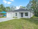 Newly built home showcasing a gray exterior, white garage, and grassy front yard at 815 S Seminole Ave, Fort Meade, FL 33841
