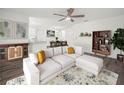 Bright living room with white sectional sofa, ceiling fan, and hardwood floors at 815 S Seminole Ave, Fort Meade, FL 33841
