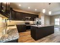 Modern kitchen featuring dark cabinets, granite countertops, stainless steel appliances, and an island at 3671 E Gaskins Rd, Bartow, FL 33830