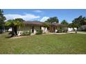 Tan single-story house with a large yard, double doors, and a white garage door at 2646 Handley Blvd, Lakeland, FL 33803