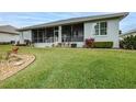 House's back features a screened porch, manicured lawn, and mature trees at 2636 Huntington Hills Dr, Lakeland, FL 33810