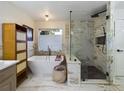 Spa-like bathroom with soaking tub, marble tile, and walk-in shower at 1323 Hammock Shade Dr, Lakeland, FL 33809