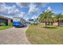 Brick paved driveway with a large RV parked, tall palm trees, and lush lawn at 544 Narrow Pond Rd, Polk City, FL 33868