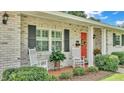 Brick home with a charming front porch, featuring rocking chairs and lush landscaping at 1175 E George St, Bartow, FL 33830