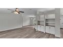 Living room with gray vinyl flooring, ceiling fan, and built-in shelving at 7120 Dove Meadow Trl, Lakeland, FL 33810