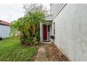 Side view of the house entrance with a red door and lush landscaping at 307 La Serena, Winter Haven, FL 33884