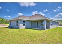 Rear view of house with covered patio and grassy backyard at 1576 Leamington Ln, Winter Haven, FL 33884