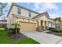 Two-story house with beige siding, a two-car garage, and landscaping at 7004 Oakwood St, Davenport, FL 33837