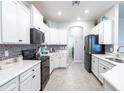 White kitchen with black appliances and mosaic backsplash at 9042 Se 49Th Court Rd, Ocala, FL 34480