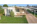 Front exterior view of a manufactured home showcasing its light-colored siding and covered carport at 6461 Hollyberry Ne Ln, Winter Haven, FL 33881