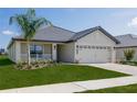 Tan house with gray roof, two car garage, and landscaping at 4645 Grandview Glen Dr, Auburndale, FL 33823