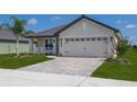 Beige house with a gray roof, two-car garage, and well-manicured lawn at 4645 Grandview Glen Dr, Auburndale, FL 33823