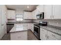 Modern kitchen with white cabinets, granite countertops, and stainless steel appliances at 5114 Villa Crest Way, Auburndale, FL 33823