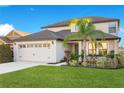 Two-story house with a two-car garage, lush landscaping, and a palm tree at 2199 Ontario Way, Lakeland, FL 33805