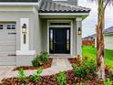 Front entrance with black door, brick walkway, and landscaping at 4443 Juliana Lake Dr, Auburndale, FL 33823