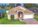Charming single-story home with a red door, landscaped yard, and brick driveway at 3226 Oak Tree Ln, Winter Haven, FL 33884