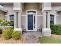 Front entrance with a navy blue door and two chairs at 332 Lake Mariana Way, Auburndale, FL 33823