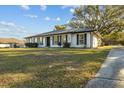 White brick ranch house with gray shutters, landscaping, and a large yard at 4409 Hallam Hill Ln, Lakeland, FL 33813