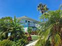 Building exterior showcasing a teal building with tropical landscaping and walkway at 541 S Peninsula Ave # A01, New Smyrna Beach, FL 32169