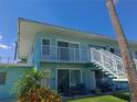 Light blue building exterior with stairs, patio furniture, and palm trees at 541 S Peninsula Ave # A13, New Smyrna Beach, FL 32169