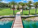 Wooden dock extending over a serene pond leading to a charming house at 3650 Pepper Ln, New Smyrna Beach, FL 32168