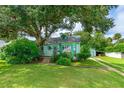 Quaint light green house with a lush lawn, mature trees, and driveway at 1206 S Riverside Dr, New Smyrna Beach, FL 32168