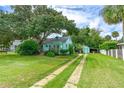 Light green house with a spacious lawn and a long driveway at 1206 S Riverside Dr, New Smyrna Beach, FL 32168