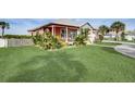 Landscaped yard of coral house with green grass and palm trees at 300 Quay Assisi Ct, New Smyrna Beach, FL 32169